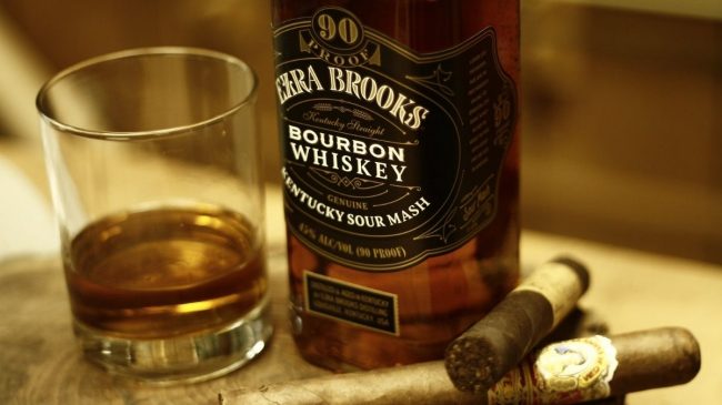ezra brooks bourbon bottle with glass and cigar