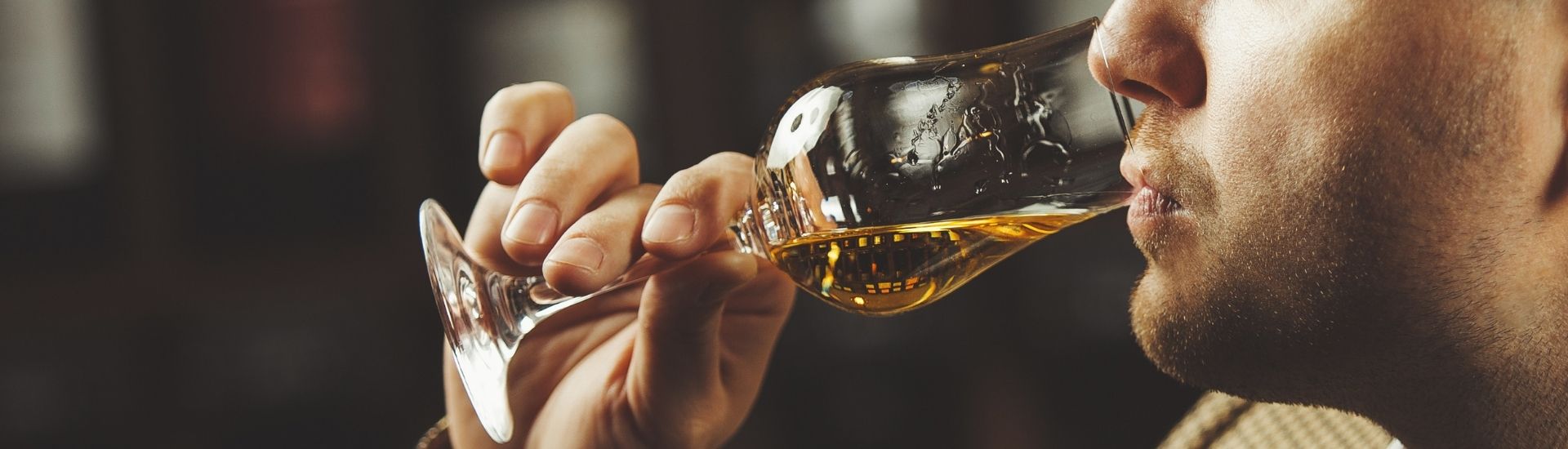 man tasting whiskey from glass